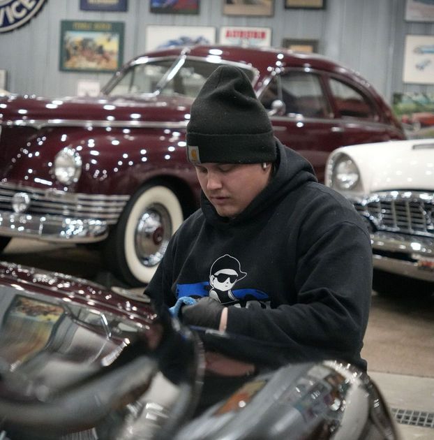 A man is working on an old car in a garage