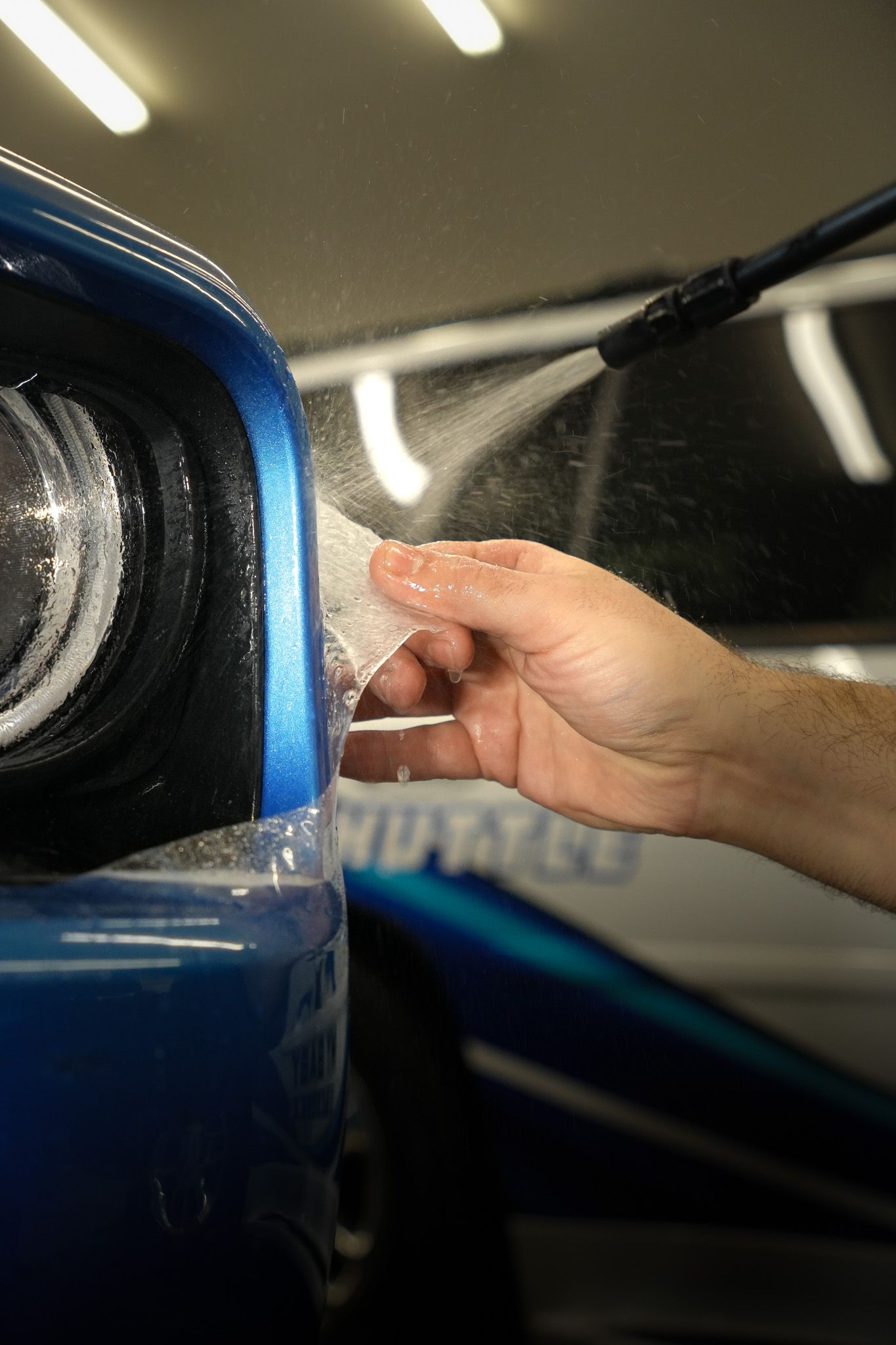 A man is working on a blue car in a garage.