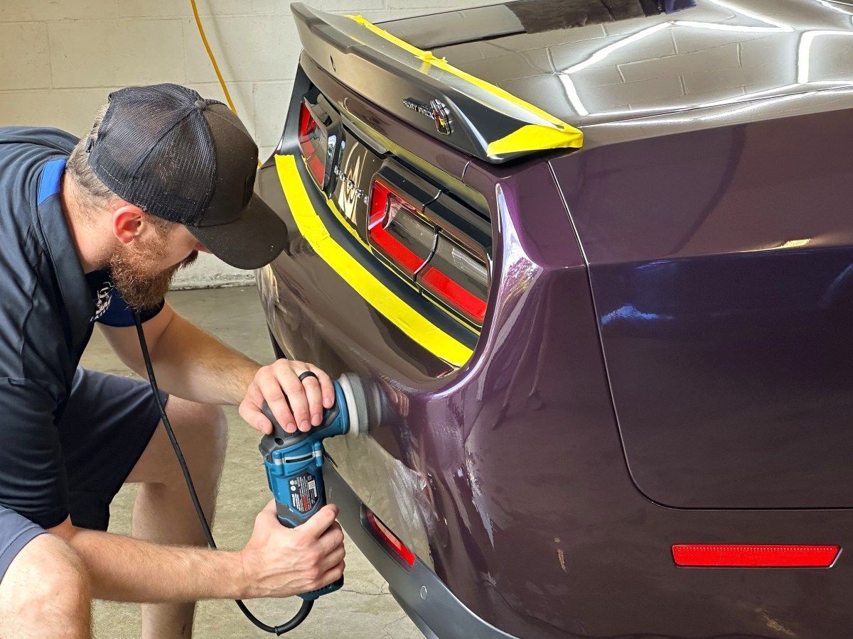 A person is polishing a car with a machine.