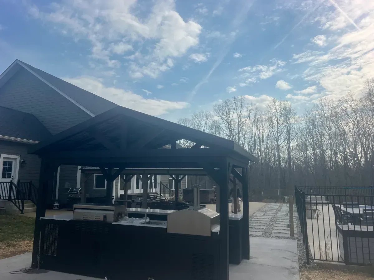 Outdoor gazebo with tables and a snowy yard under a cloudy sky