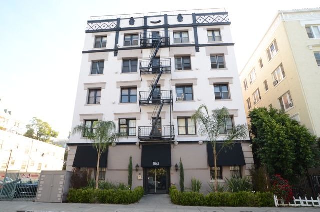 Multi-story white building with black accents and a fire escape.