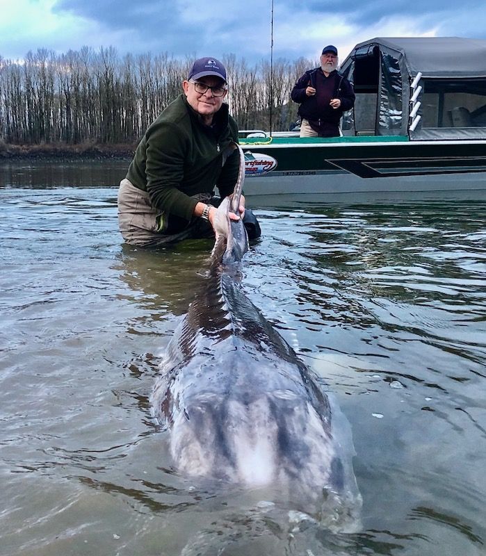 A man in a black hoodie is holding a large fish