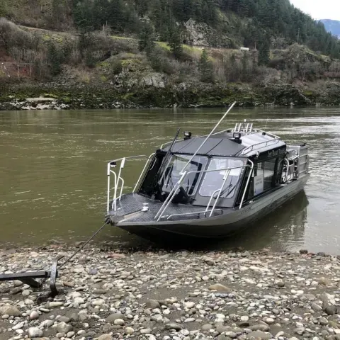 A boat is sitting on the shore of a river.