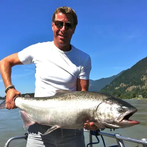 A man is holding a large fish on a boat