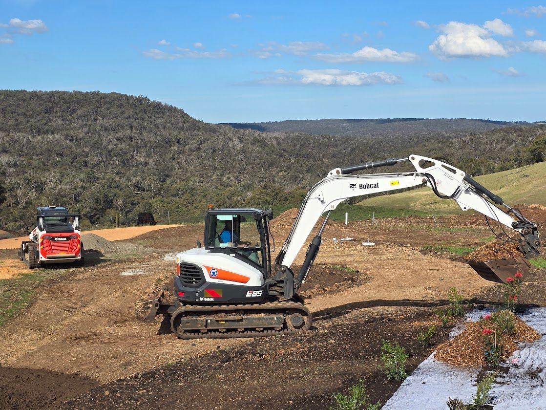 A bulldozer is digging a hole in front of a building.