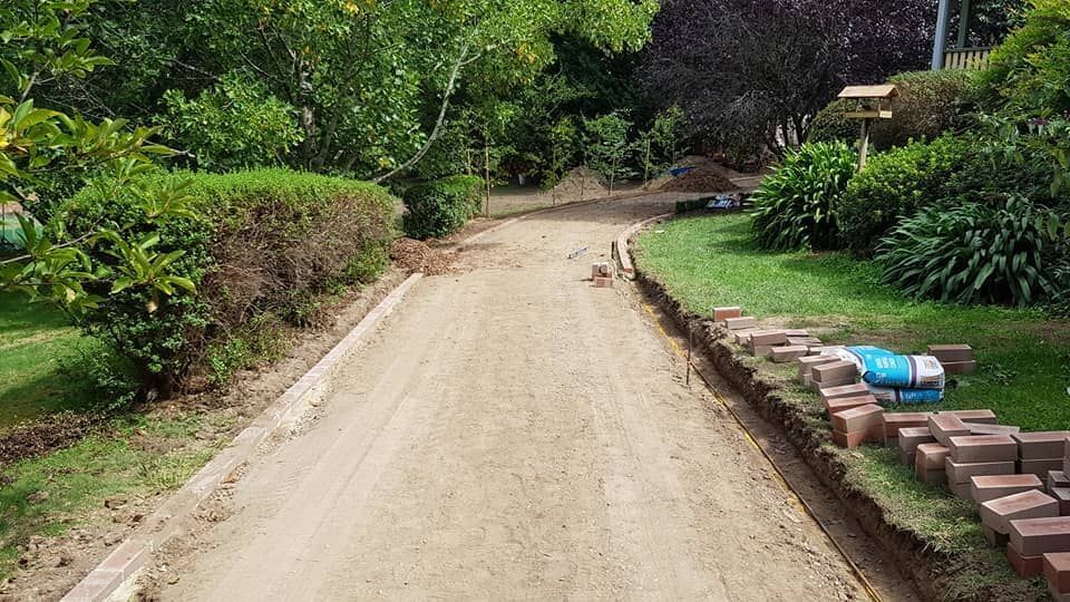 A dirt road going through a park with bricks on the side of it.