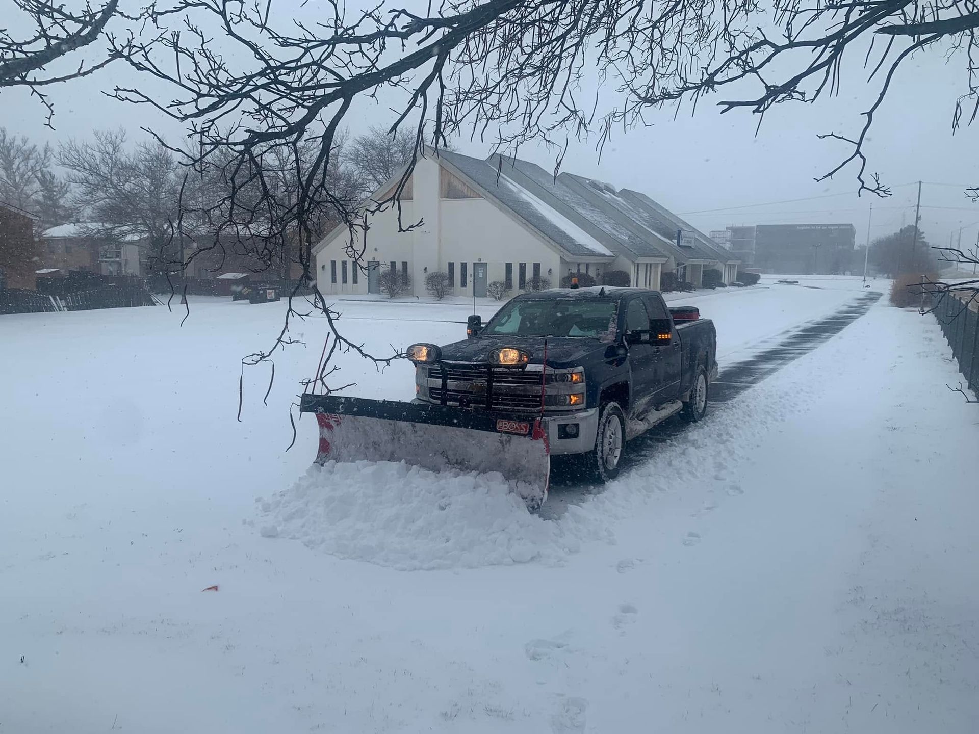 Snowplow clearing a snowy road beside a house on a winter day