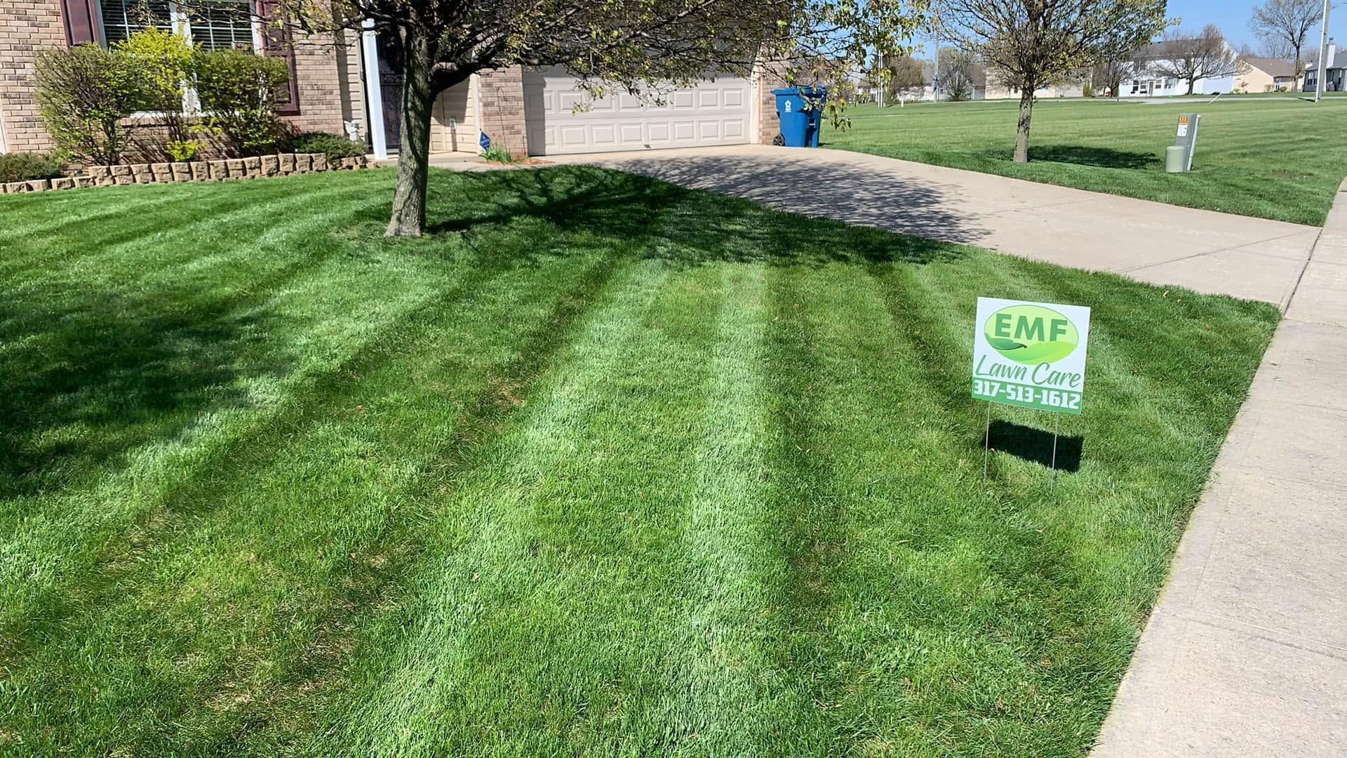 Green lawn with a small yard sign beside a sidewalk near a building
