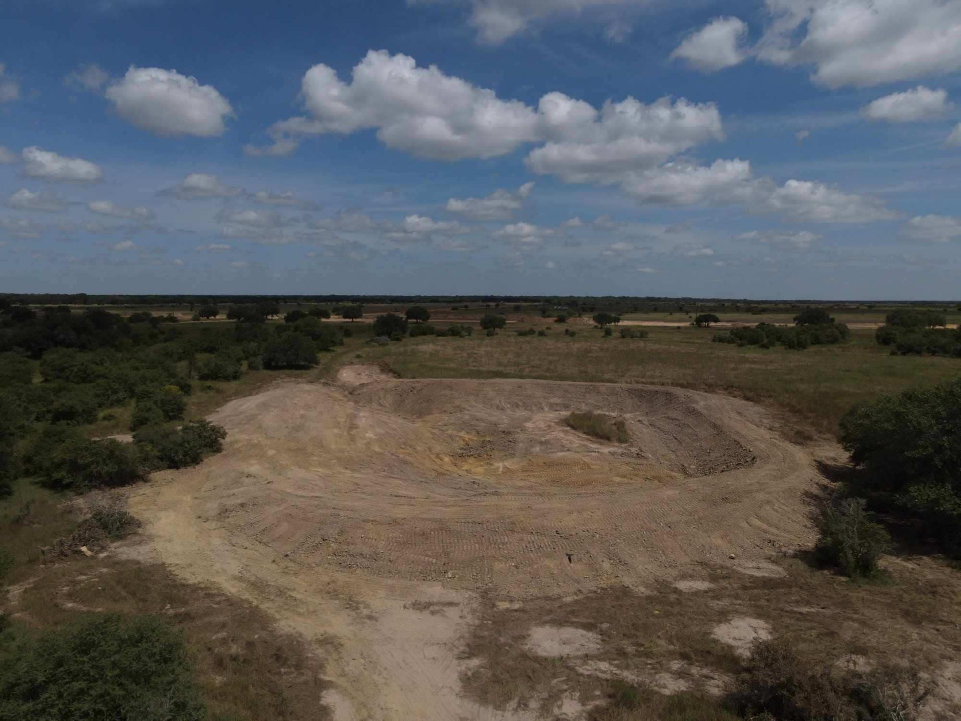 Texas pond construction project with excavator working near water