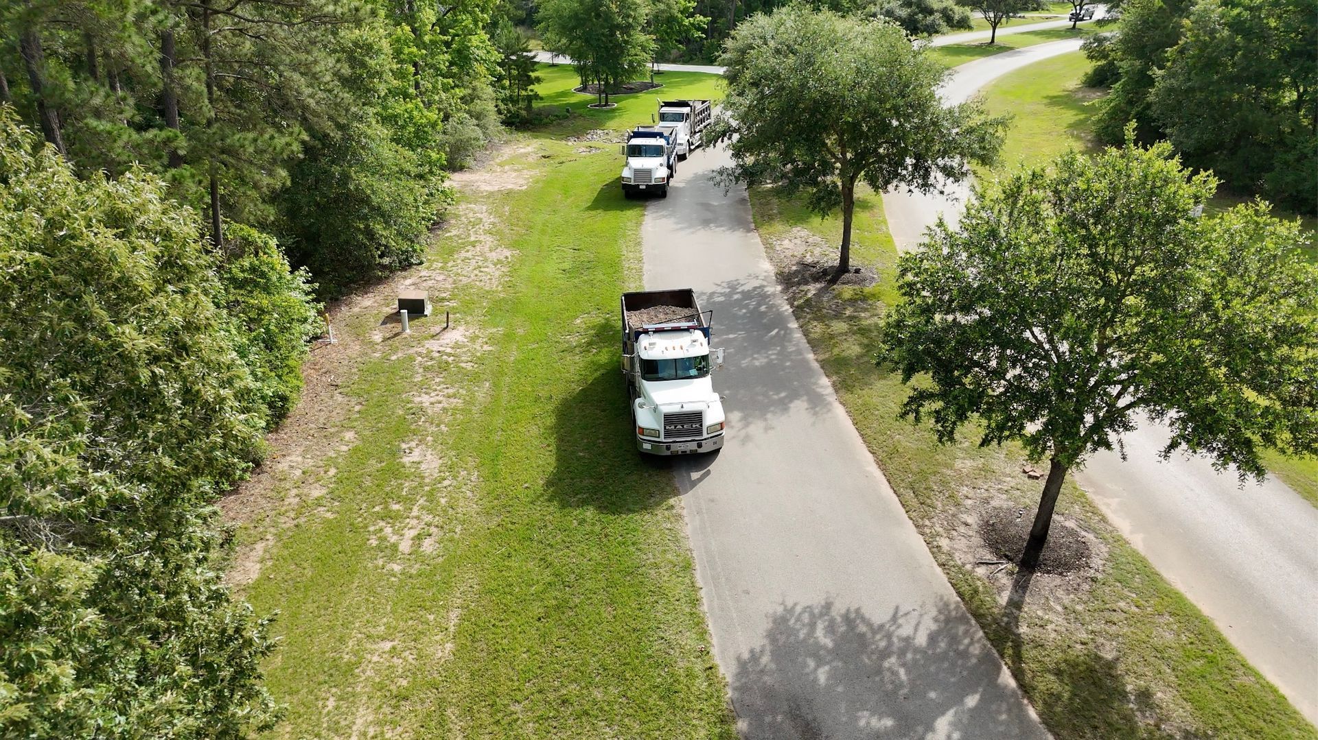 Trucks delivering imported fill material for a pond draining and filling project in Montgomery Texas