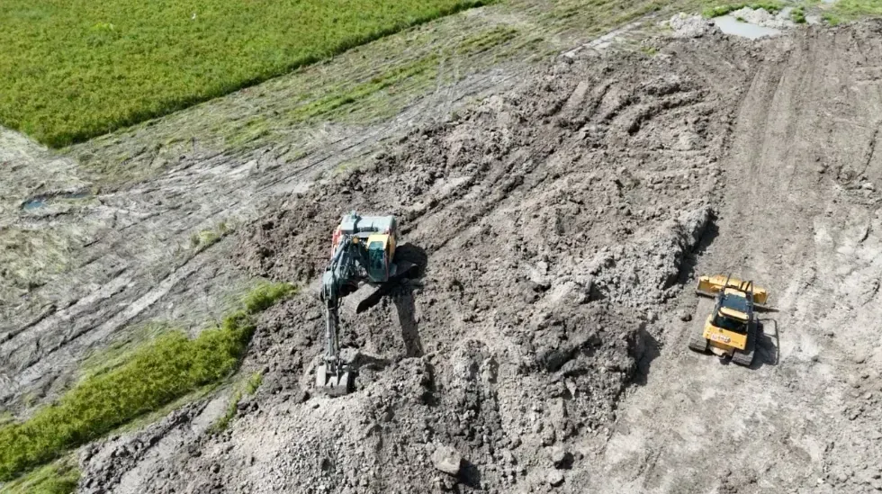 Excavator and dozer moving native soil during pond construction in Cat Spring, Texas