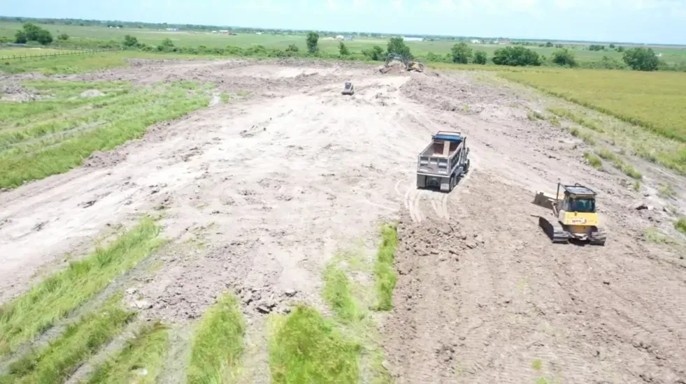 Dump truck and dozer spreading excavated pond material across the surrounding Cat Spring acreage