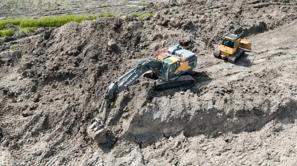 Excavator cutting into the one-acre pond footprint during construction in Cat Spring, Texas