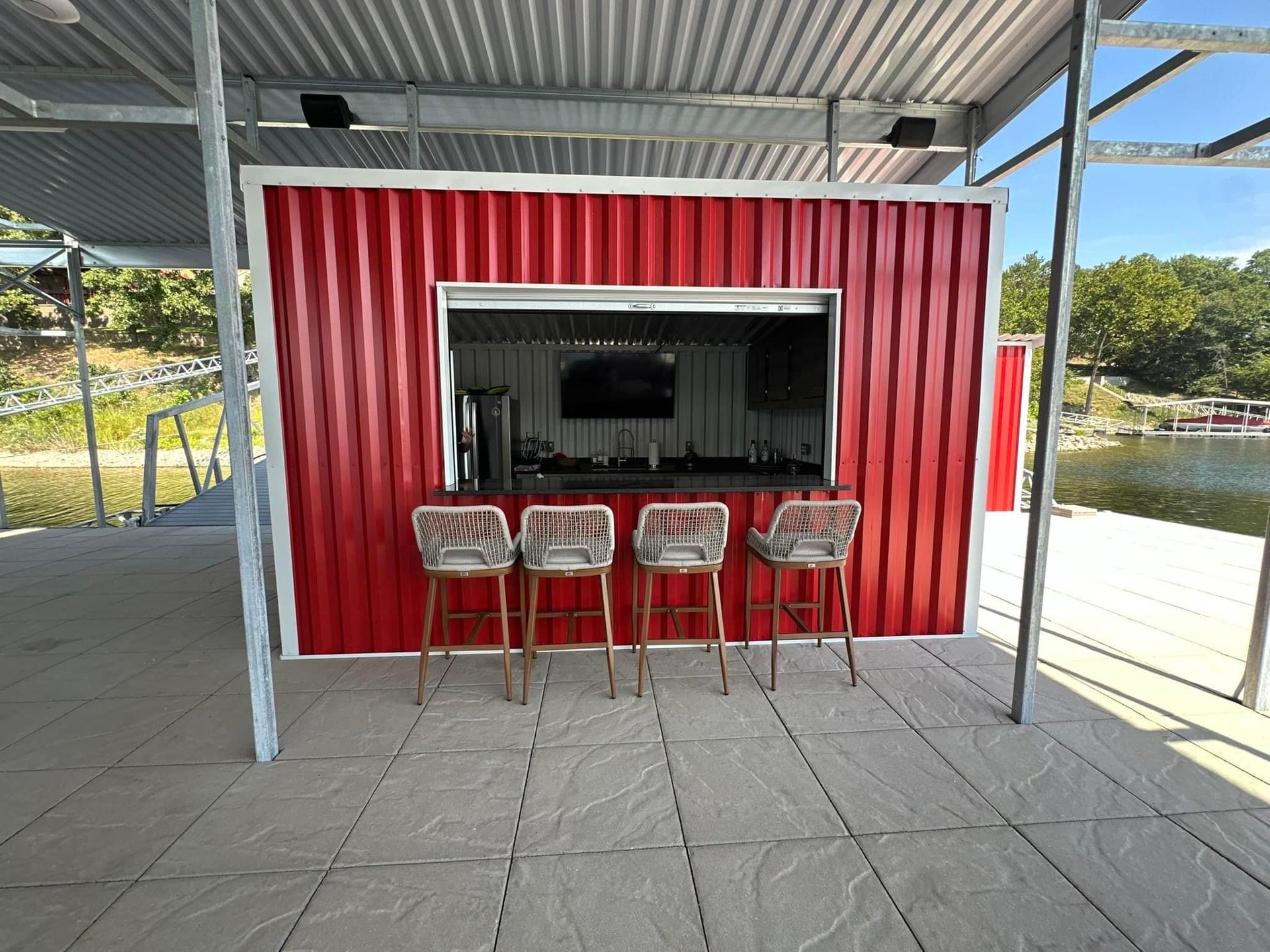 A red building with a bar and stools in front of it.