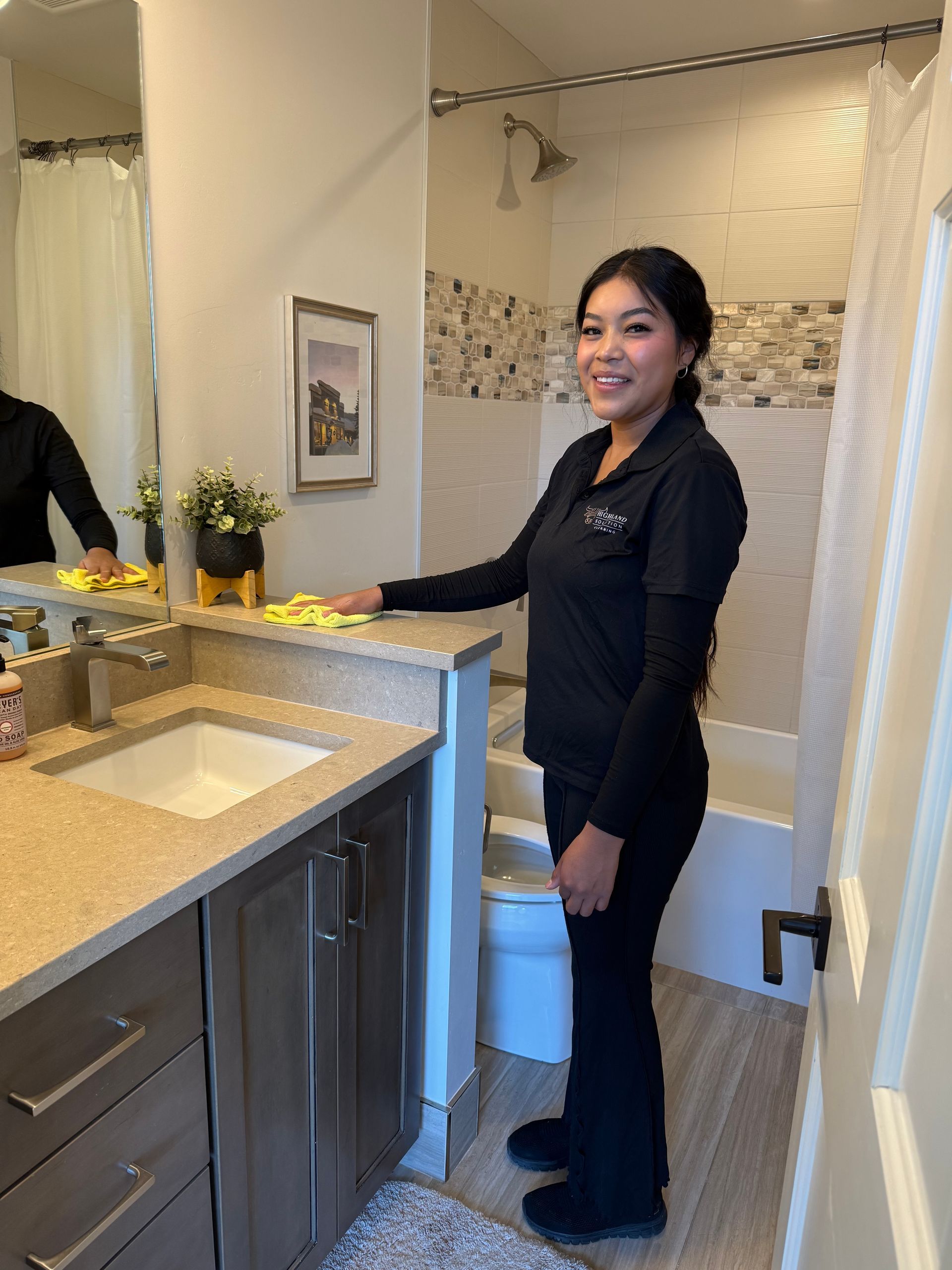 Woman in yellow gloves cleaning kitchen counter and sink.