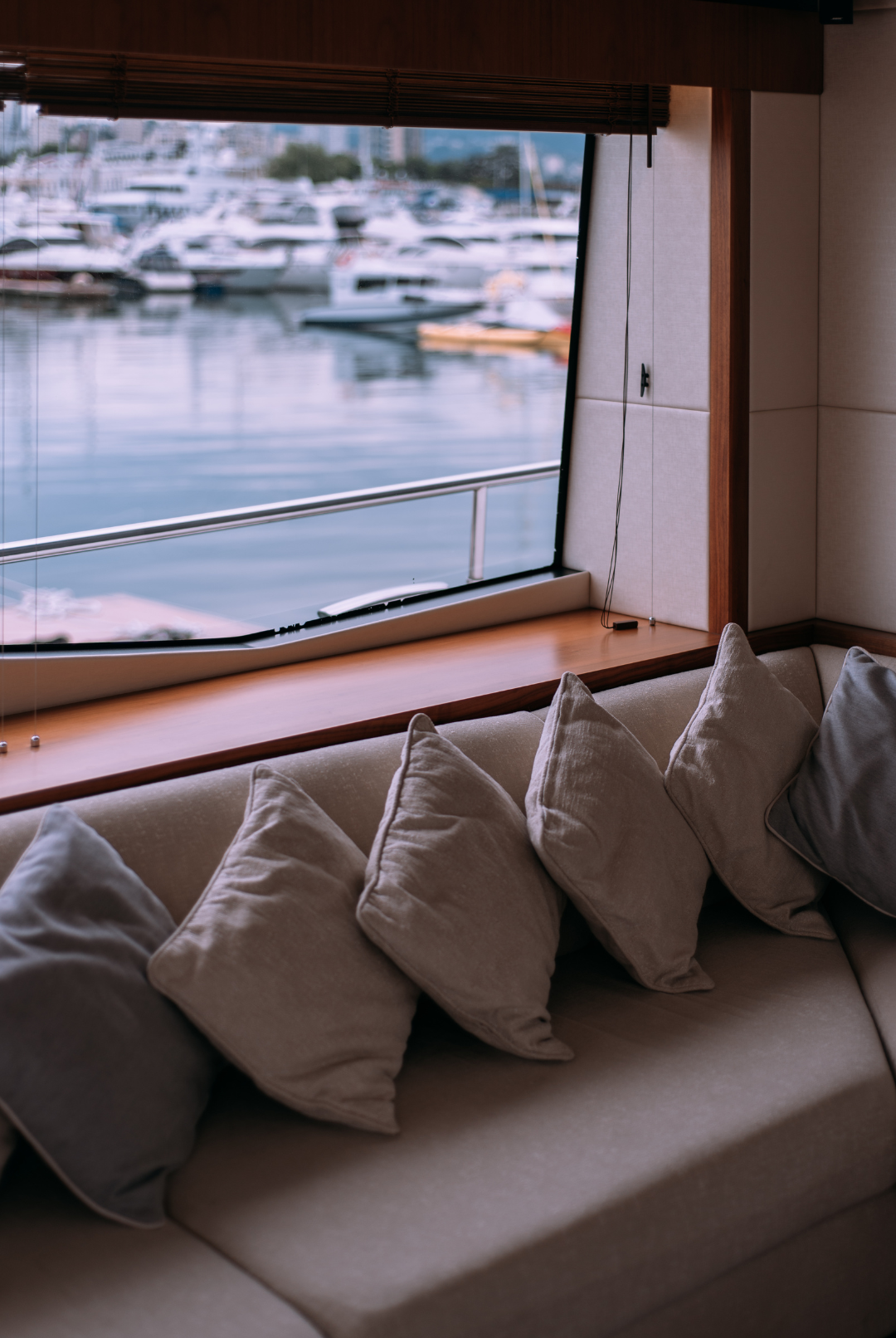 A living room with a couch and pillows and a window overlooking the water.