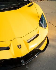 A yellow lamborghini aventador is parked on the side of the road.