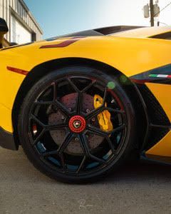 A close up of a yellow sports car with black wheels.