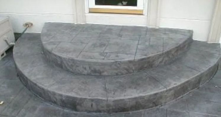 Curved concrete steps leading to a doorway, textured gray surface.