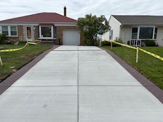 Fresh concrete driveway between two suburban homes with grass and red brick borders