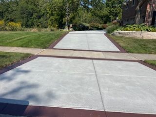 Concrete walkway through a landscaped courtyard with grass, trees, and brick buildings nearby