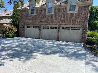 Brick house with three-car garage and a wide concrete driveway in bright sunlight