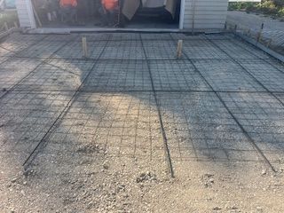 Concrete patio with wire mesh and two wooden stakes in front of a house entrance