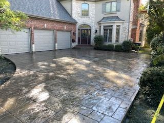 Large brick house with three-car garage and a wide stone driveway in front.