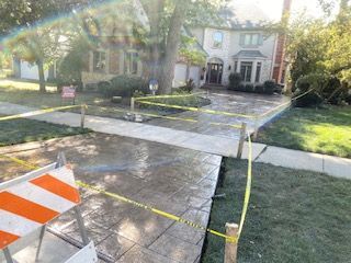 Closed sidewalk and driveway with orange barricade tape in front of a house