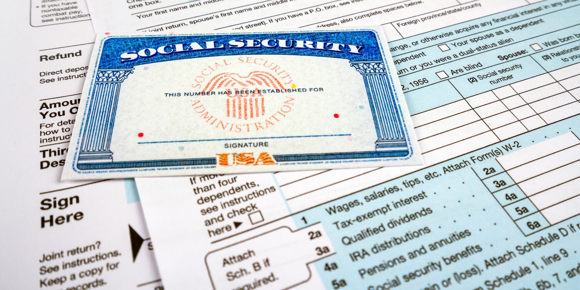 Blue medical document or ID card lying on paperwork with a “Sign Here” label visible nearby