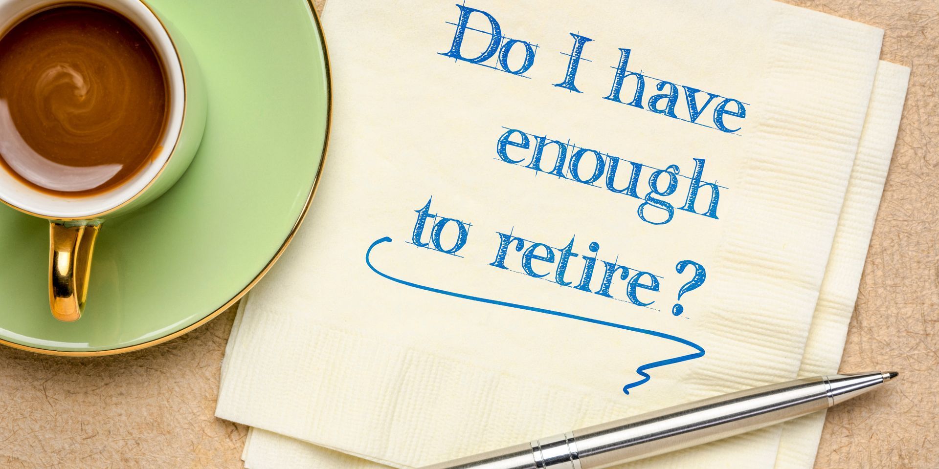 Notebook with blue text asking “Do I have enough to retire?” beside a coffee cup and pen