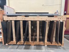 Wooden crate with angled black metal panels in a workshop or warehouse setting