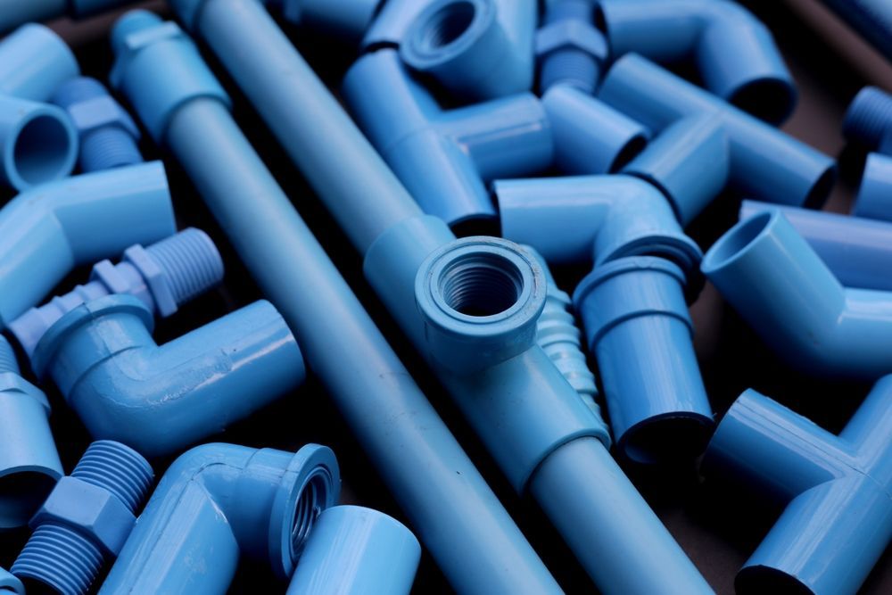 Pile of blue plastic pipe fittings and connectors on a surface