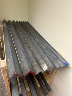 Stacked metal roofing panels leaning against a wall in a small storage area