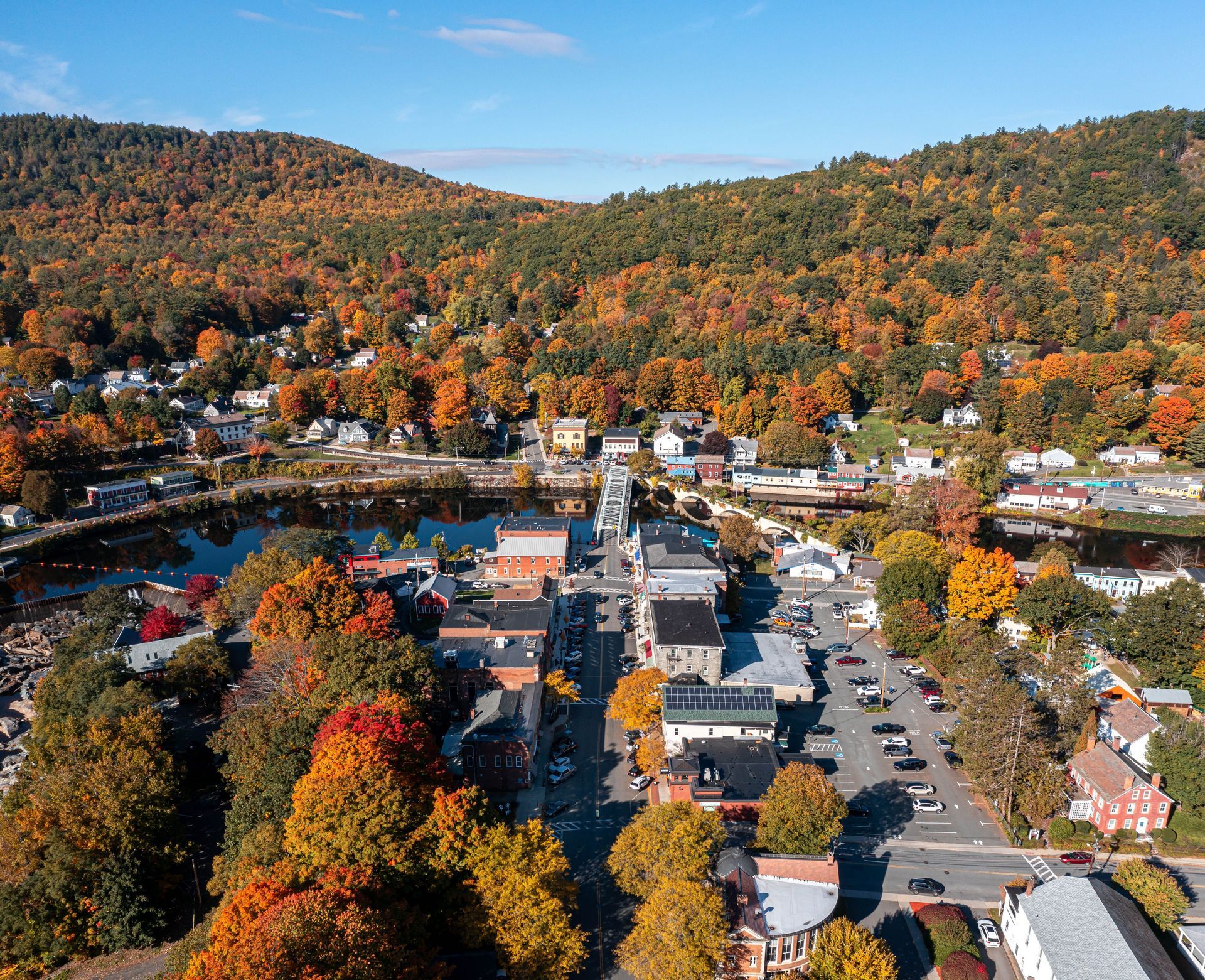 Aerial view of a town with colorful autumn trees surrounding buildings and a river.