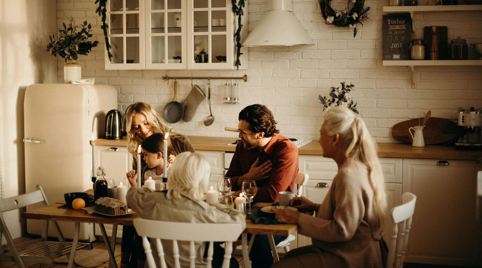 Family gathered around a wooden table in a warm kitchen. Sunlight streams in.