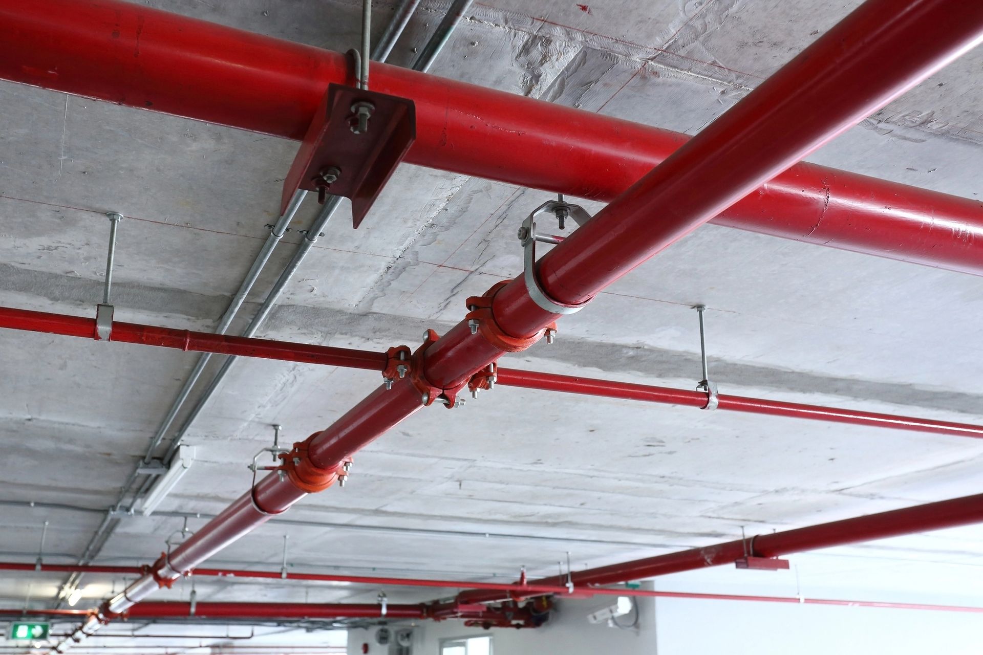 A bunch of red pipes are hanging from the ceiling of a building.