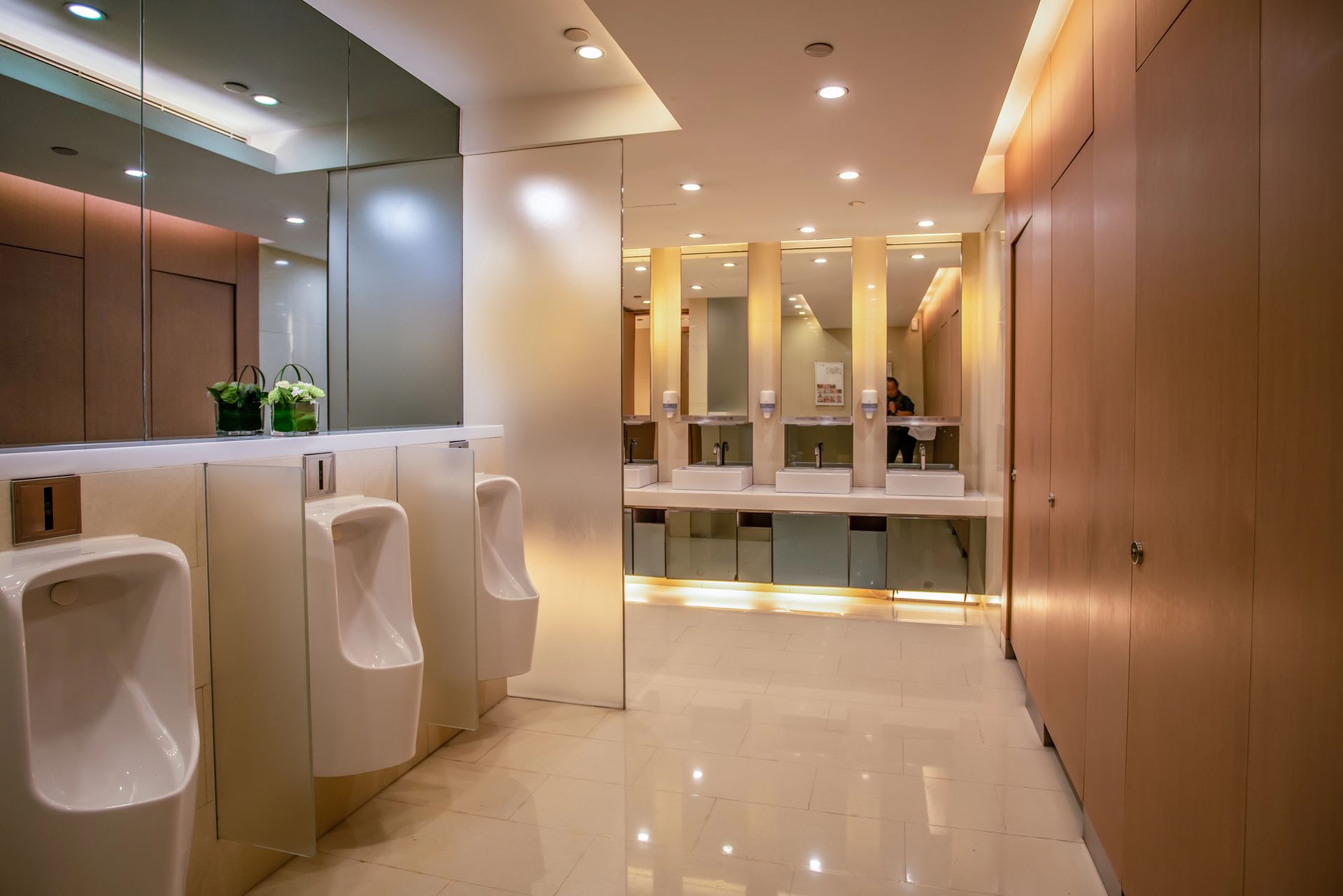 A public restroom with urinals , sinks and mirrors.
