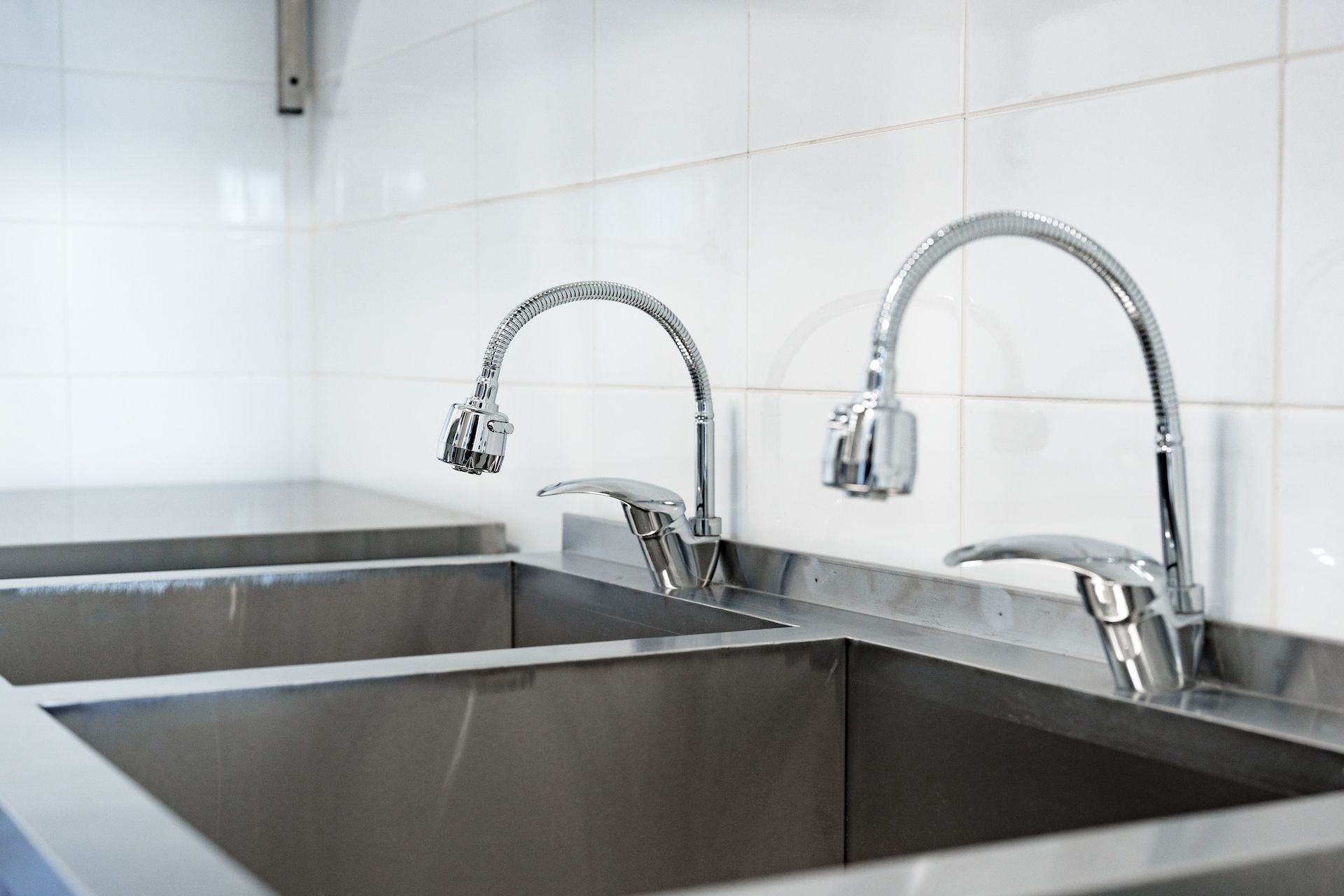 A stainless steel sink with two faucets in a kitchen.