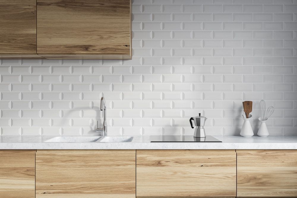 A Kitchen With White Tiles, Wooden Cabinets, A Sink And A Stove Top Oven — Standfast Cabinets In Tuggerah, NSW