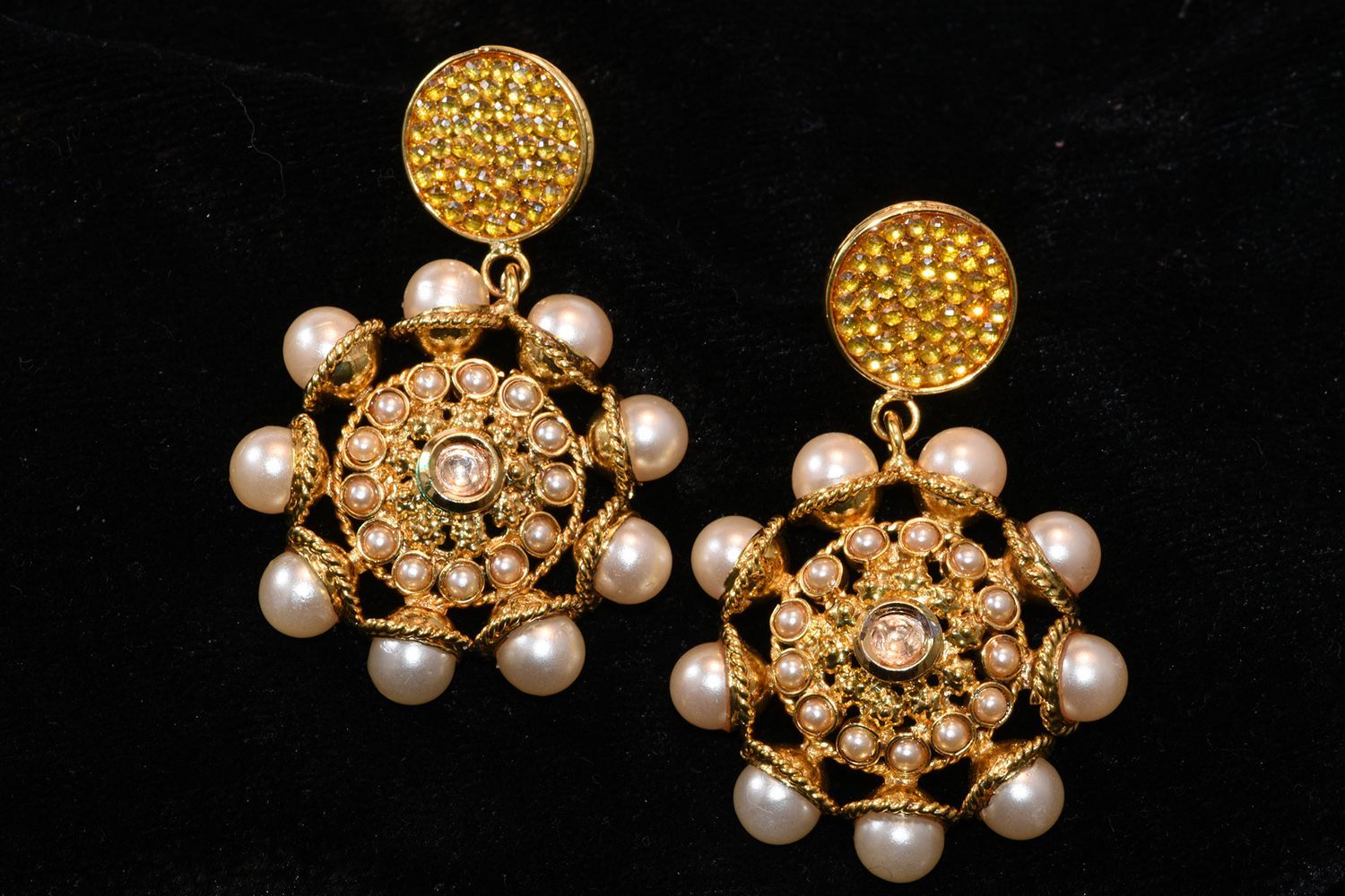 Gold earrings with pearl accents, against a black backdrop. Gold earrings with pearl accents, against a black backdrop.