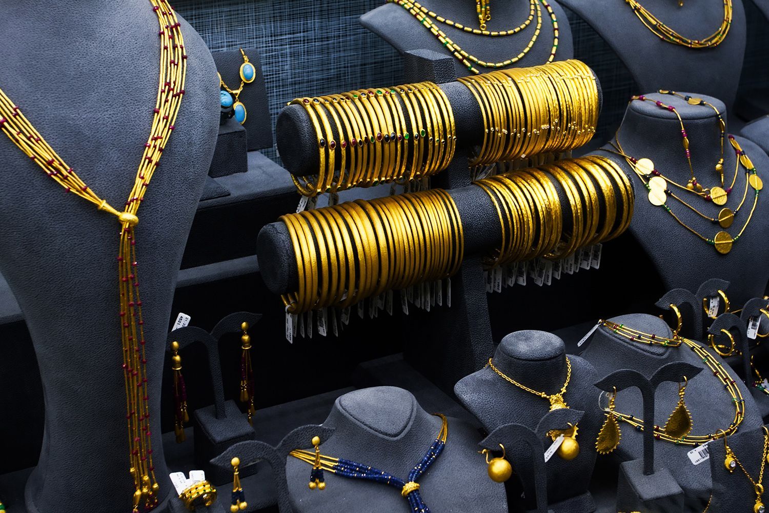 Gold jewelry display on black velvet busts and stands. Bangles, necklaces, earrings.