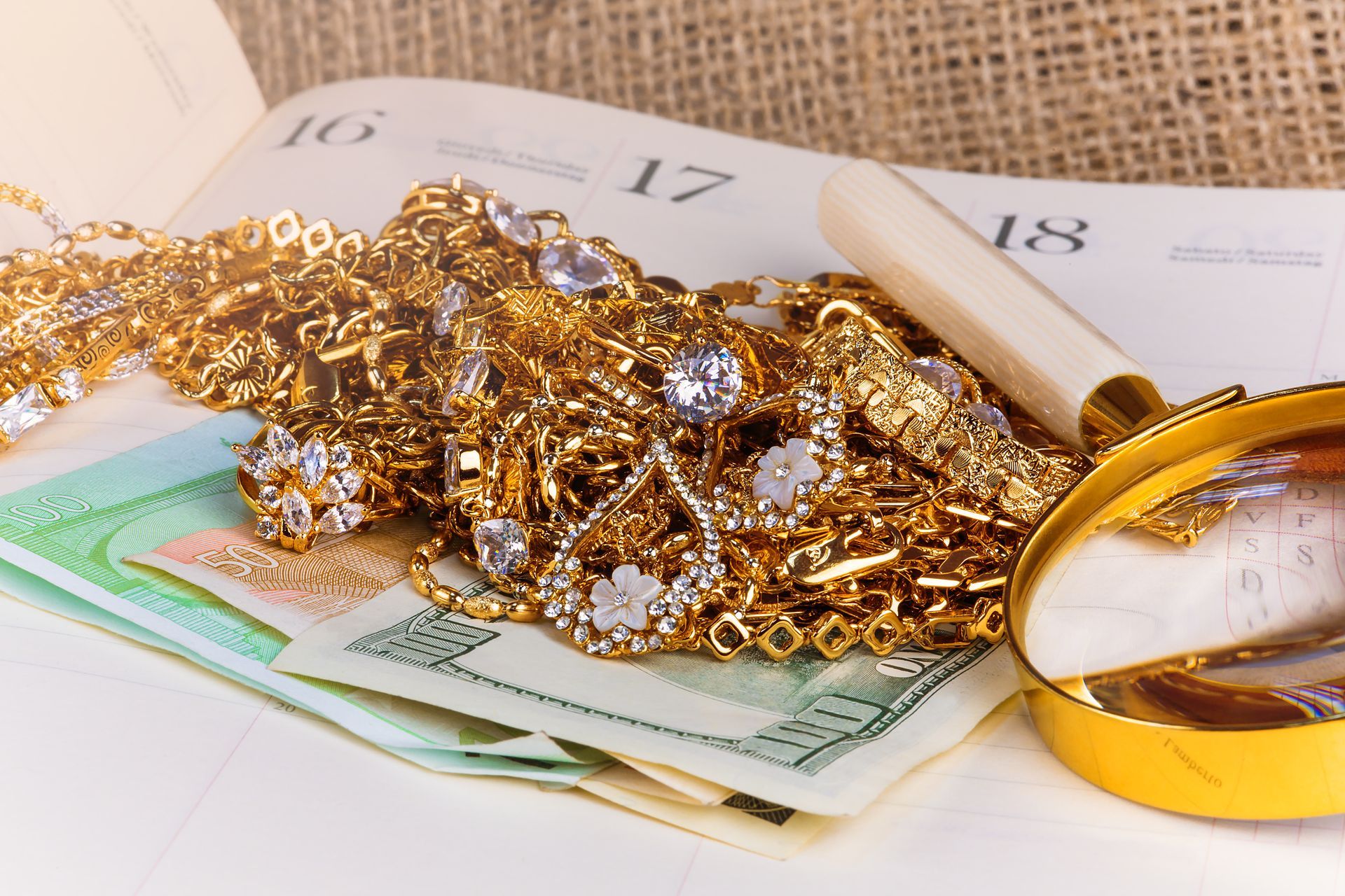 Gold jewelry and coins on a calendar, with euro banknotes and a ring on a yellow surface Gold jewelry and coins on a calendar, with euro banknotes and a ring on a yellow surface