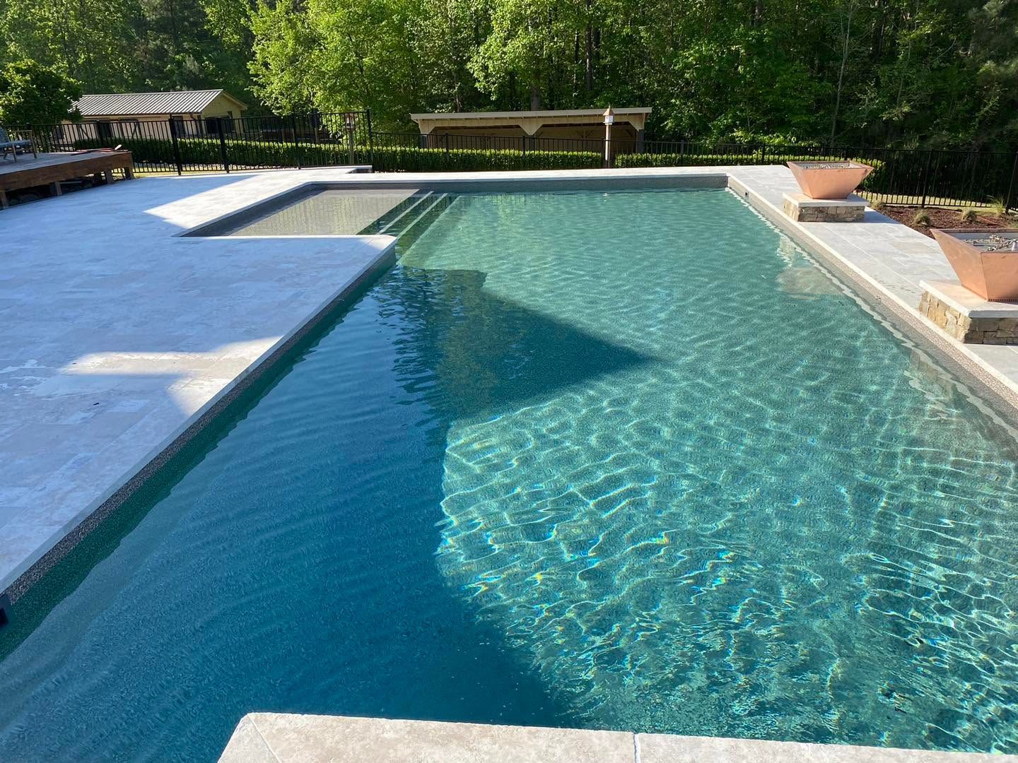 Backyard swimming pool with clear turquoise water and surrounding stone deck