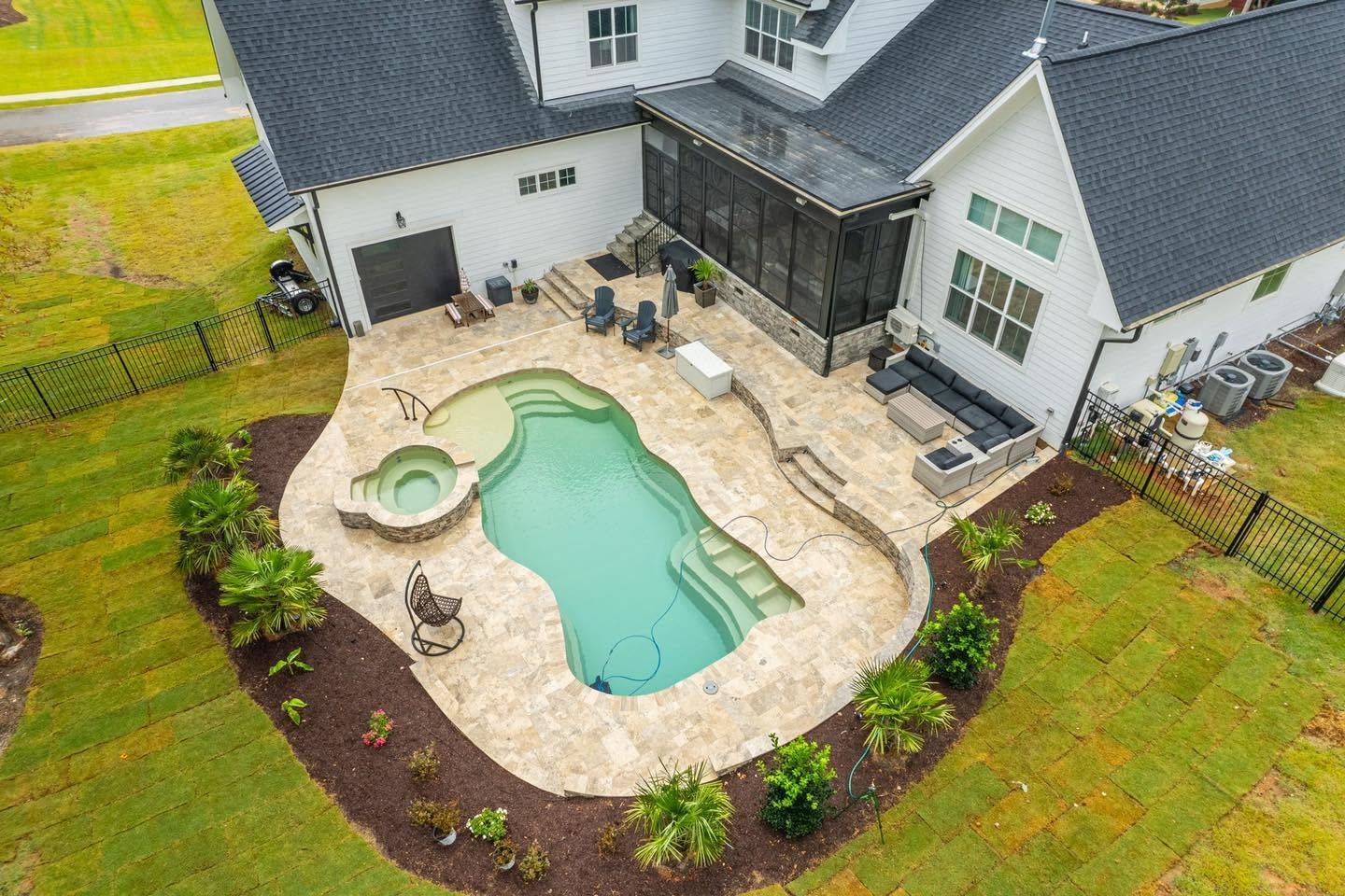 Single-story beige house with patio, large windows, and green lawn on a sunny day