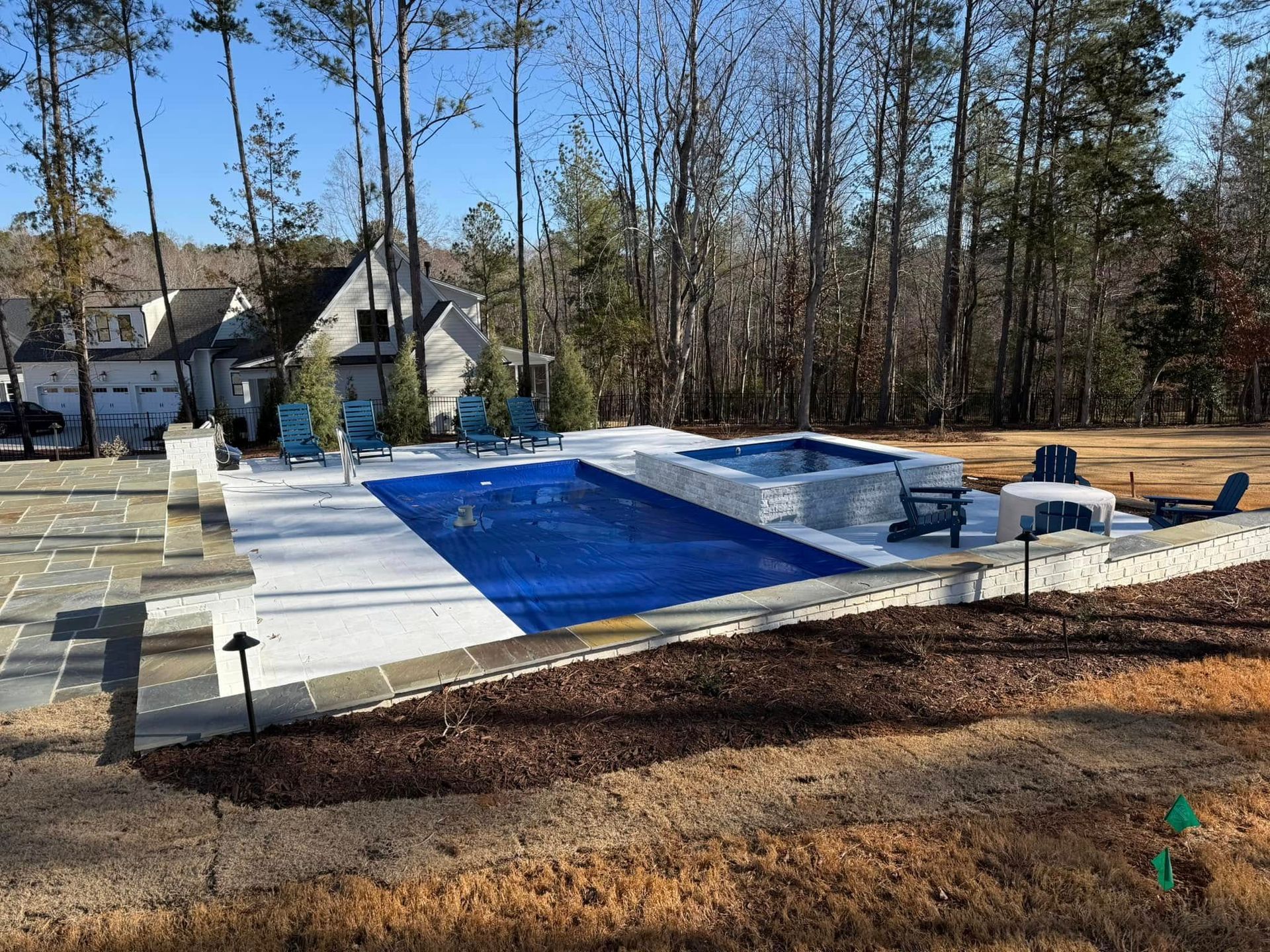 Backyard pool under construction with blue liner, concrete deck, and trees in the background