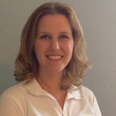 A woman in a white shirt is smiling for the camera.