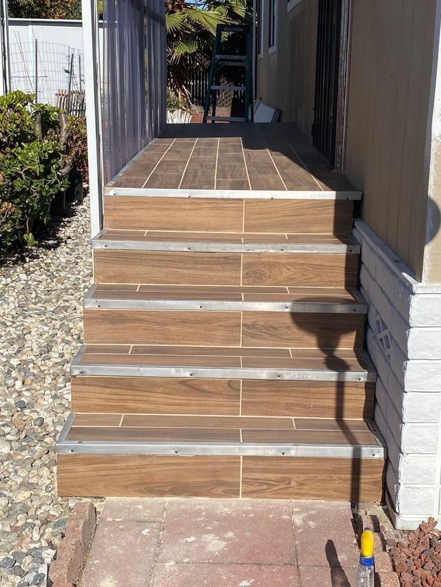 Front steps with wood-look tile leading to a covered porch entryway