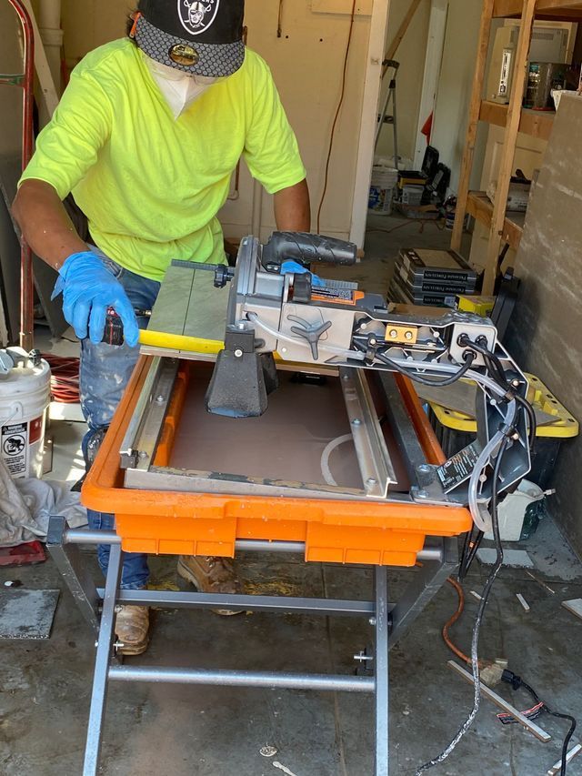 Worker in neon shirt and gloves cutting wood on a table saw in a workshop