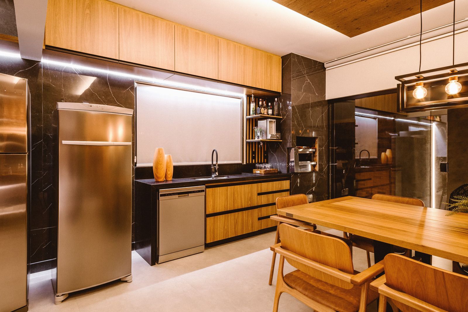 Modern kitchen with stainless steel appliances, wood cabinets, and a wooden dining table